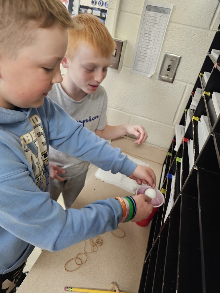 Students are passing a ping pong ball around without touching it.