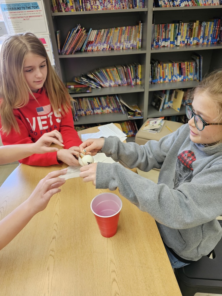 Students are passing a ping pong ball around without touching it.