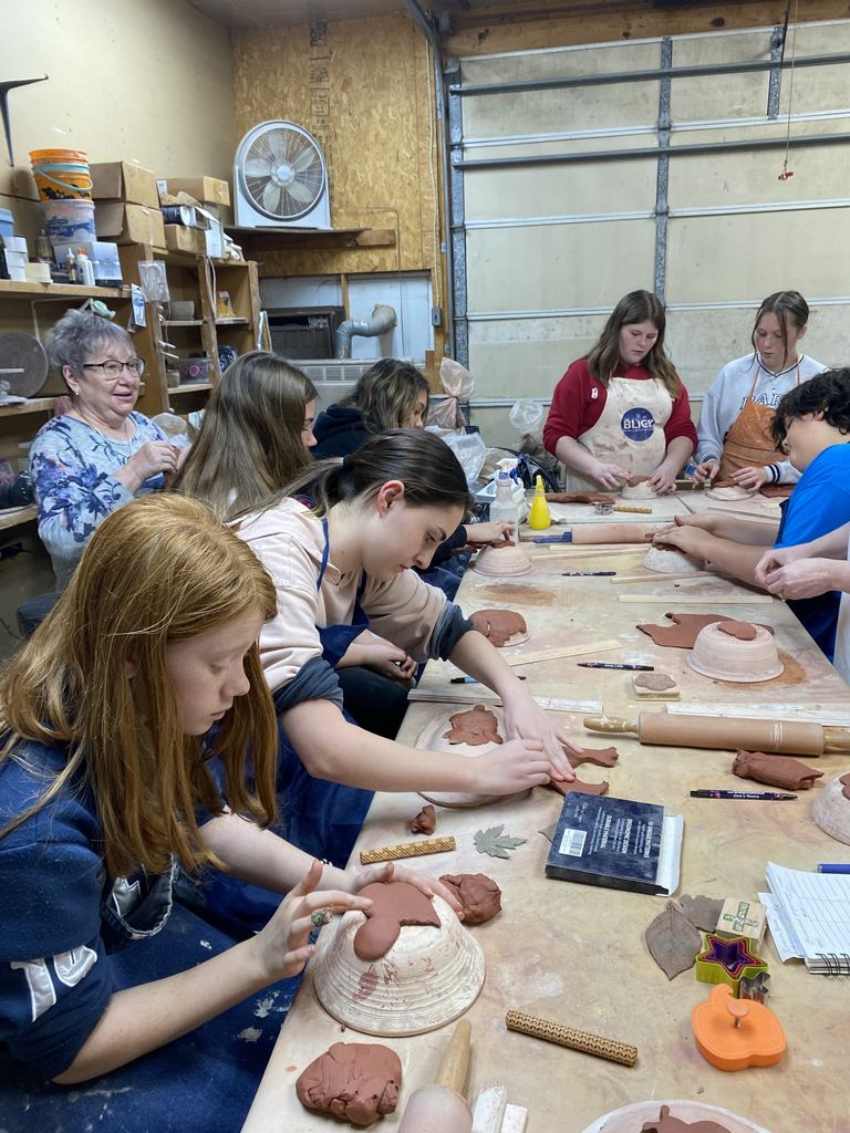 Art students are molding clay into a pot.