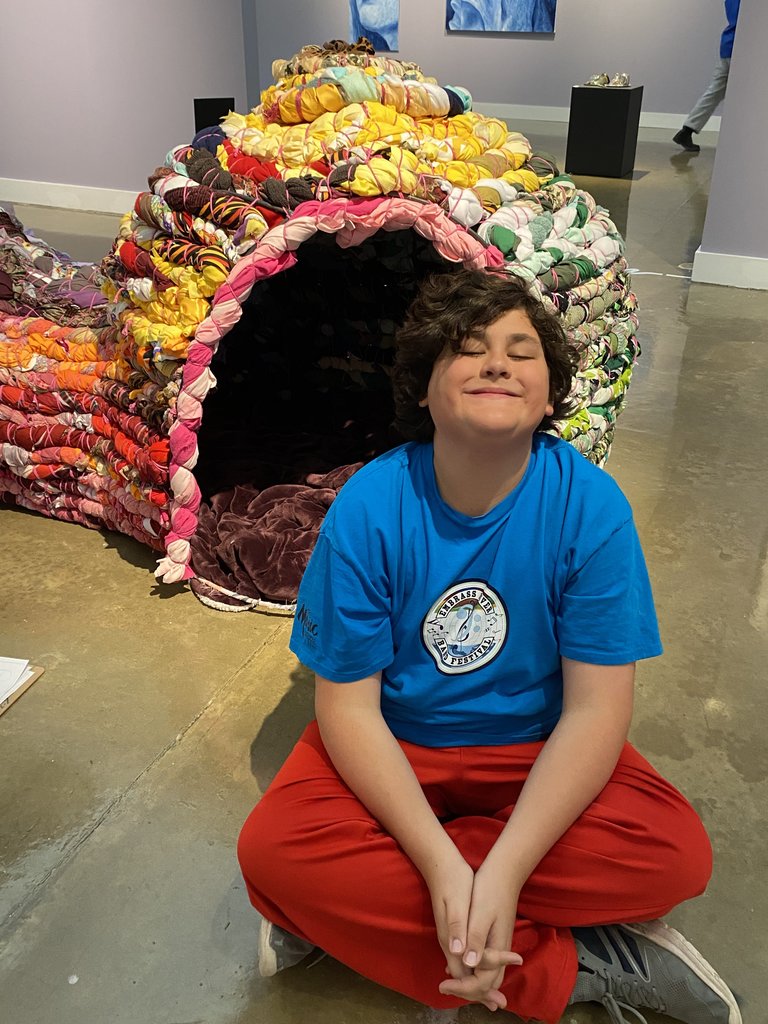 An art student is sitting in front of an art display.