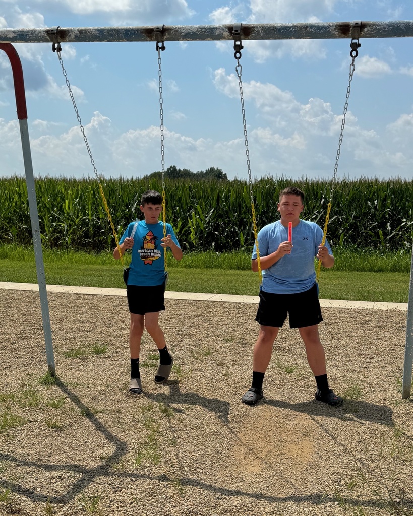 Two boys are swinging with their popsicles. 