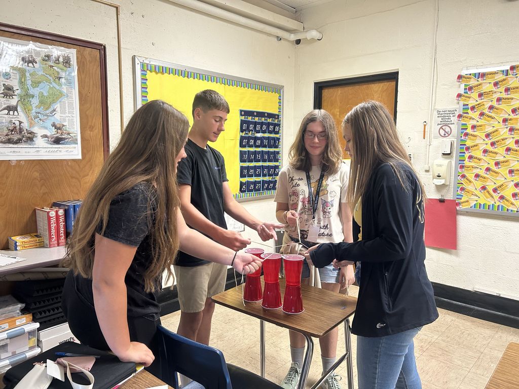 Students are collaborating to build a cup tower.
