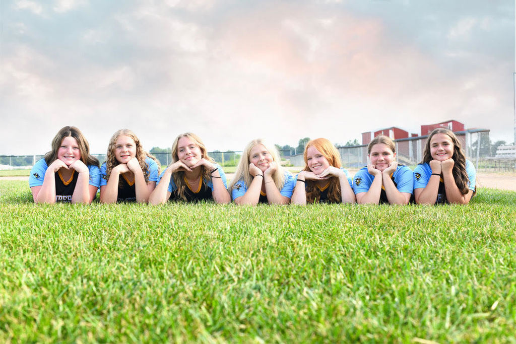 The girls are lying on the grass facing the camera.