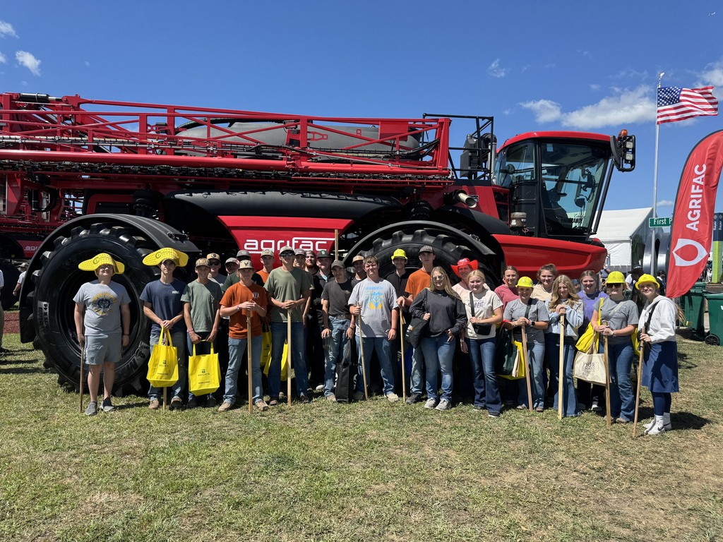 The 27 members of the FFA are standing in front of a tactor.