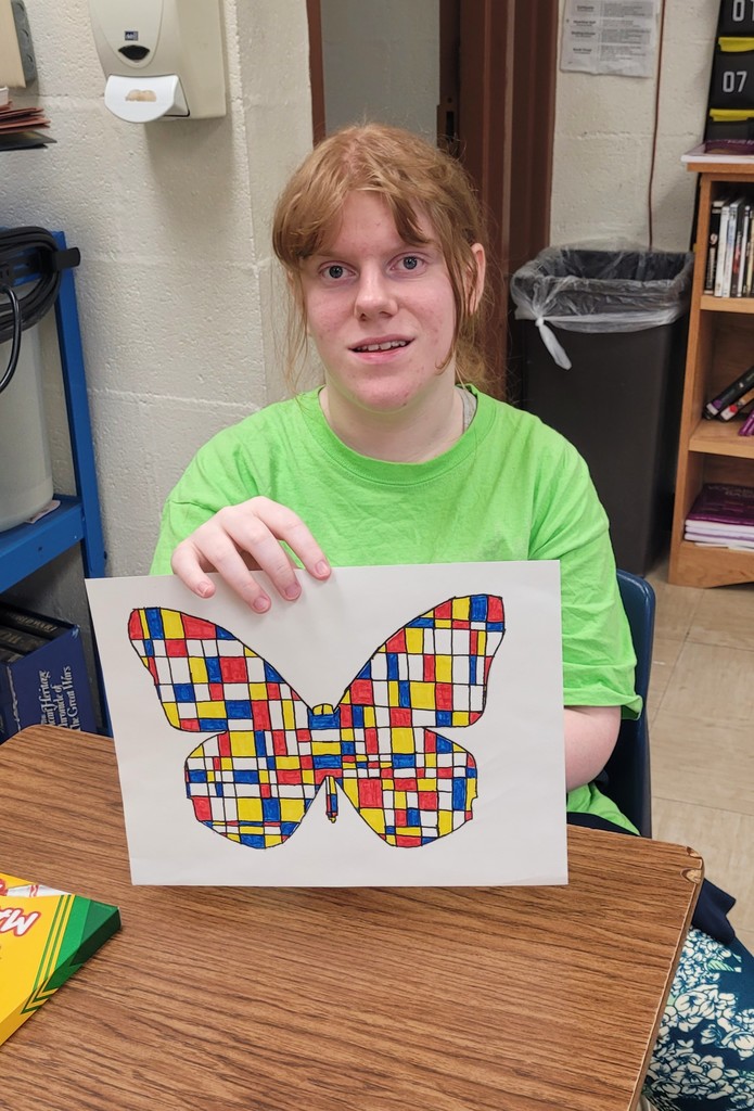 Student is holding her Mondrian art project.