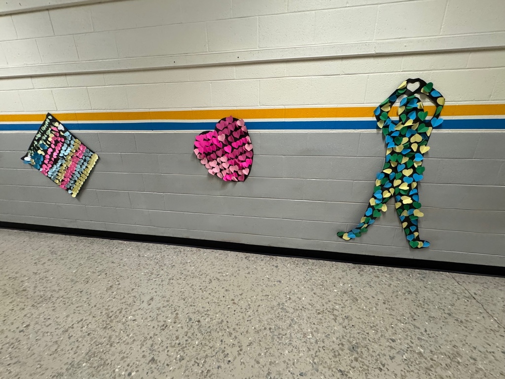 A joyful black paper figure with arms raised and one leg lifted, decorated with large pastel-colored hearts in pink, yellow, and green. To the right is a bright heart made of orange, pink, and yellow triangle-shaped papers.