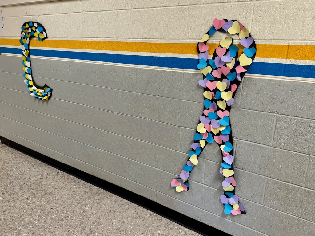 A heart-covered silhouette in a ribbon-like pose with arms above the head, made from pastel heart cutouts. Next to it is a large letter "C" formed with blue, white, and yellow paper hearts.