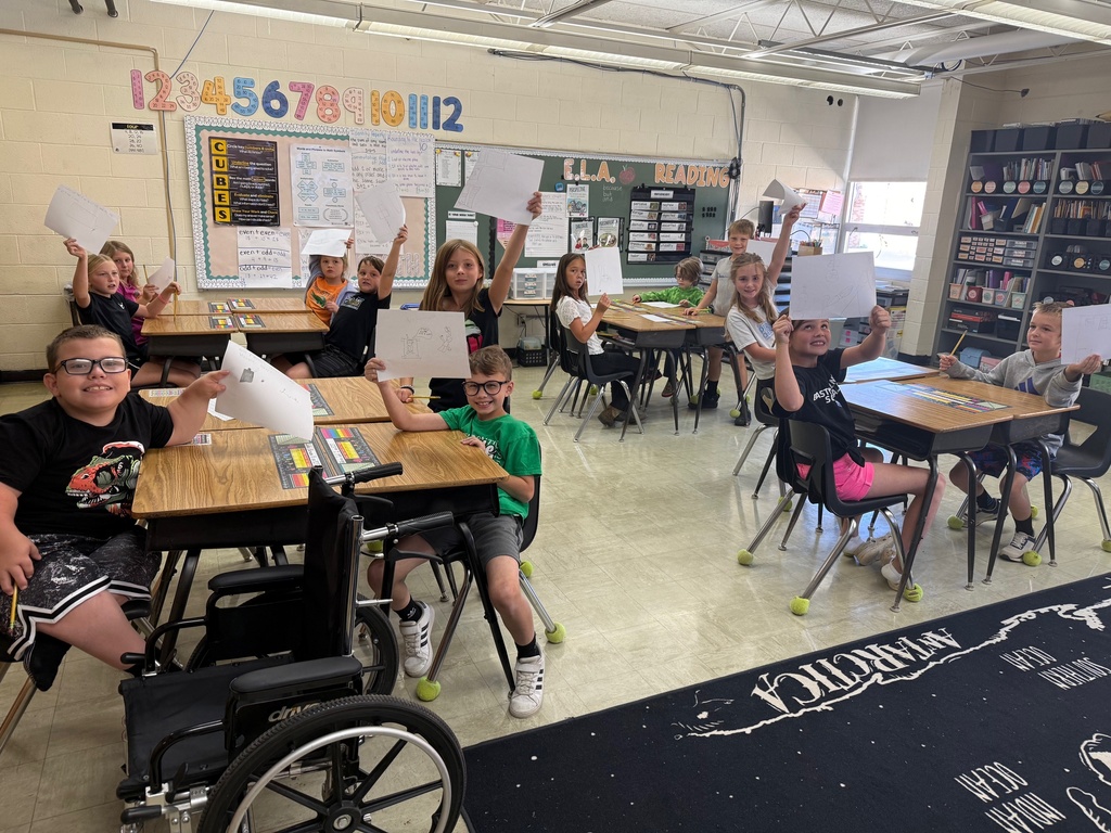Students are holding up the pictures of their illustration. 