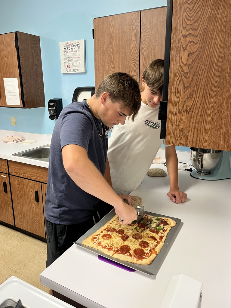 Two students are cutting their pizza.