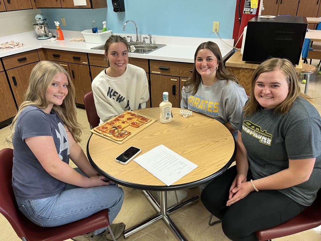 Four students are sitting around the table with their pizza.