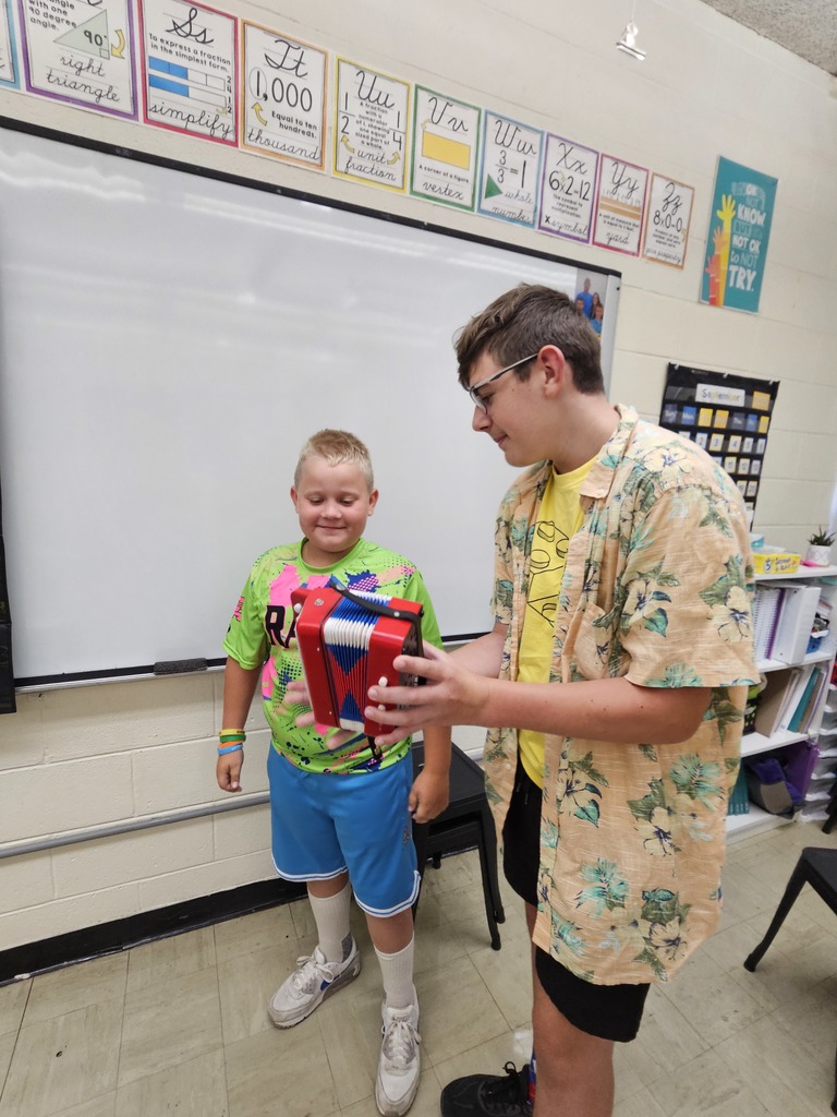 Brooks is showing a student how to play the accordian.