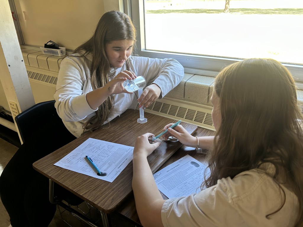 The students are using their new understanding of SI units to measure some beans and hypothesize what would happen when they were left in water overnight.
