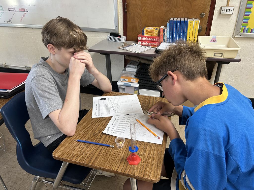 The students are using their new understanding of SI units to measure some beans and hypothesize what would happen when they were left in water overnight.