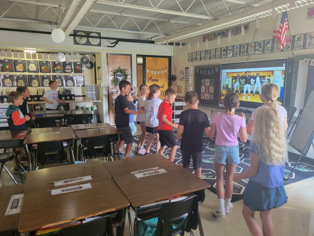 The class is standing and following the actions of the video.