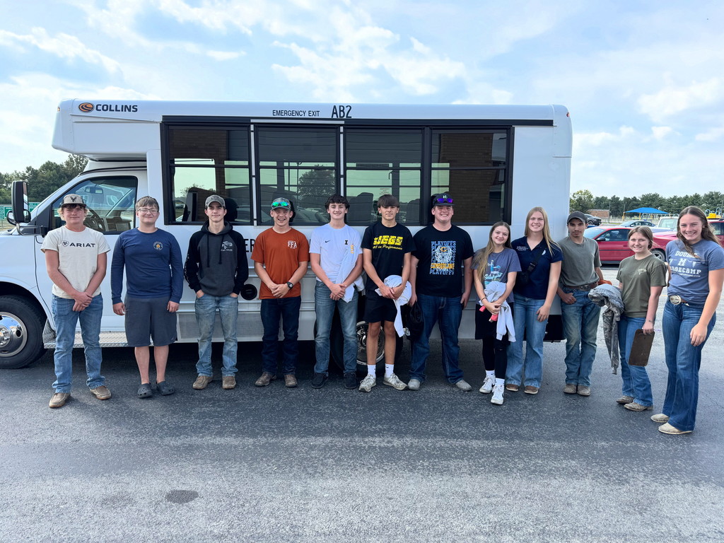 Students are standing outside of their bus before they leave for the judging contest.