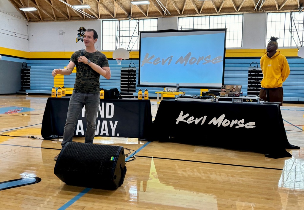 Brad is speaking to the students. Singer Kevi Morse is in the background. 