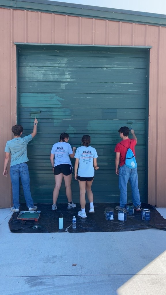 Four students are painting a garage.