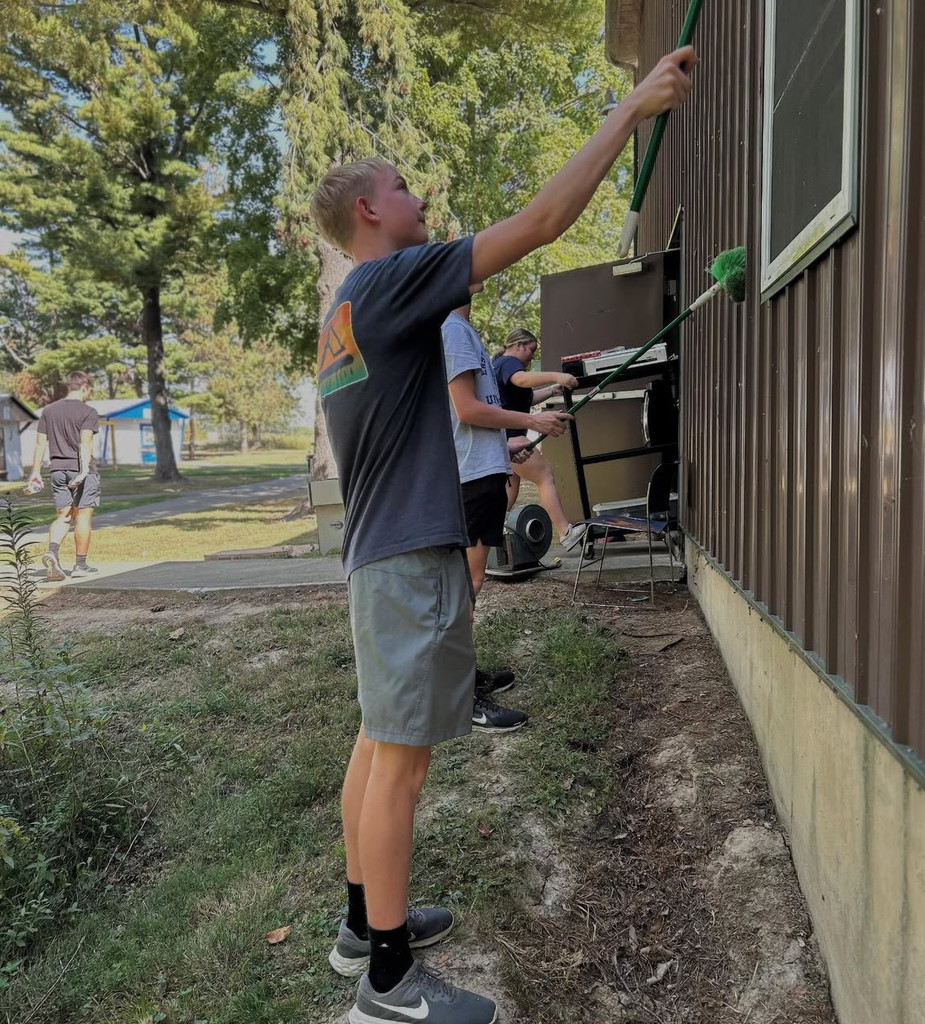 Two students are painting a cabin.