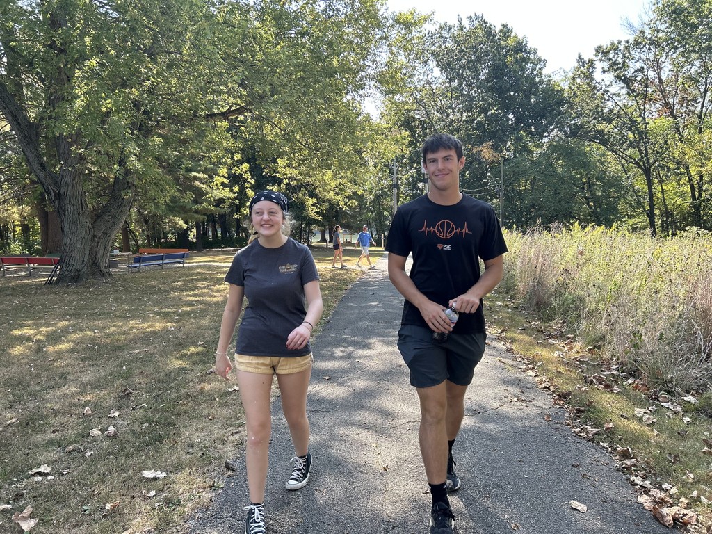 Two students are walking a trail.