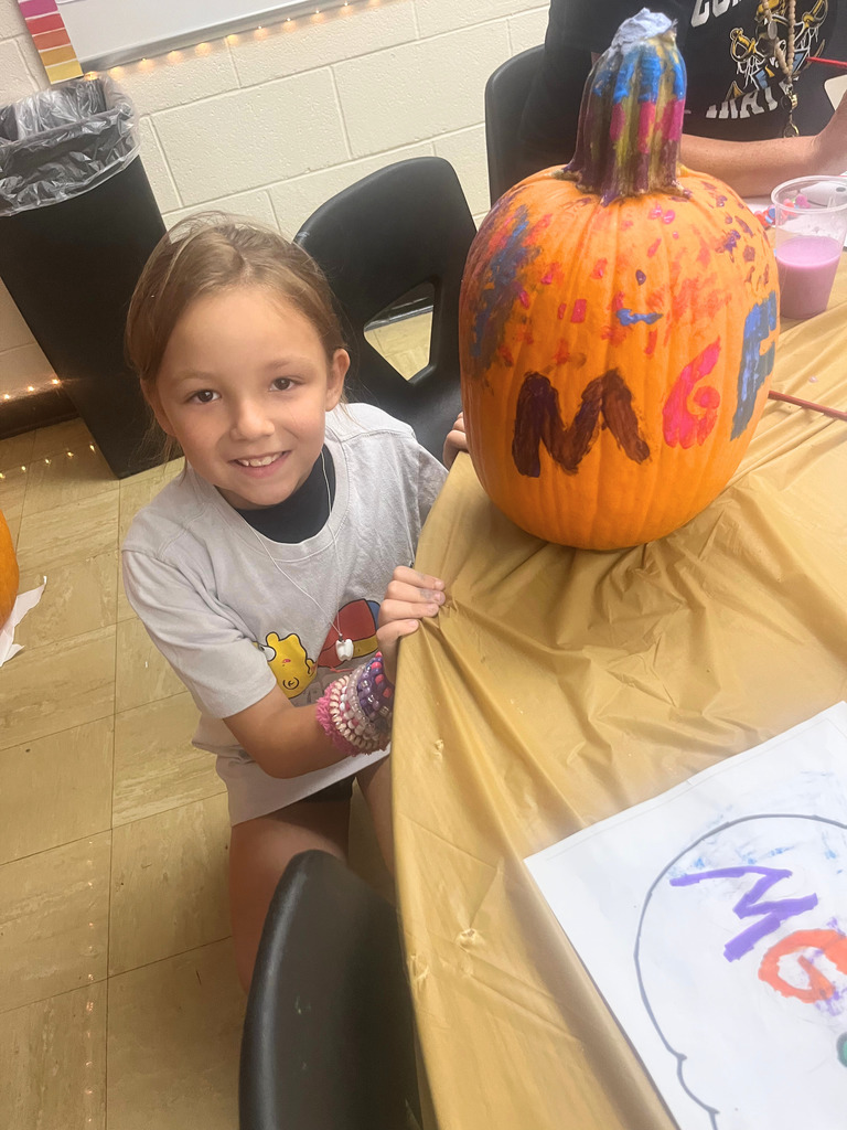 A student is posing with the pumpkin.