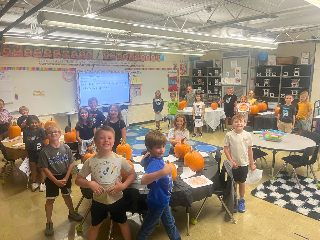 The whole class is standing next to their pumpkins.