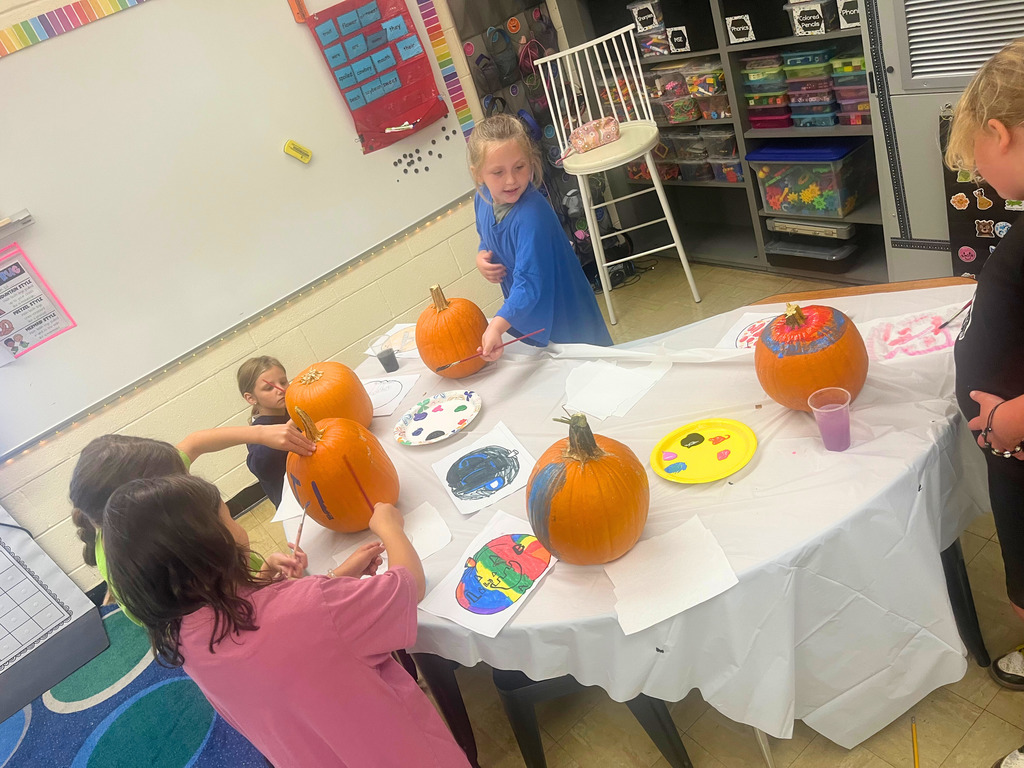 Students are painting their pumpkins. 