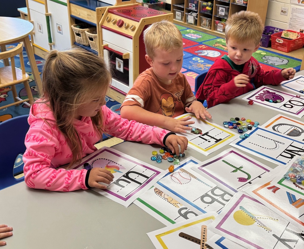 Students are tracing letters with jewels. 