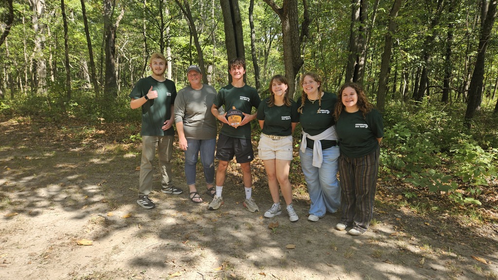 This is an image of the team with their sponsor. One member is holding their acorn trophy.