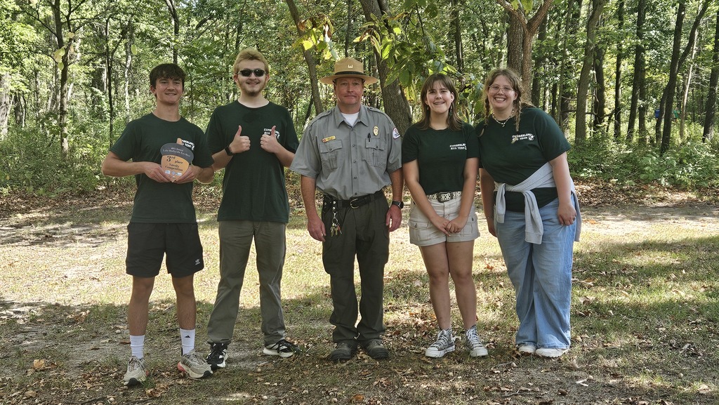 This is an image of the team with a ranger. One member is holding their acorn trophy.