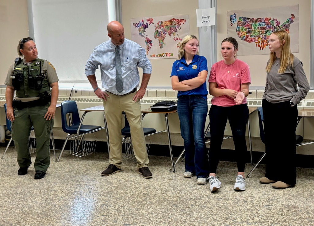 A student is defending her opinion. Students, the SRO, and an administrator are listening.