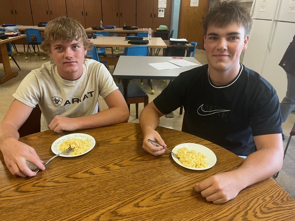 Two students are sitting at a table witht their dish of mac and cheese.