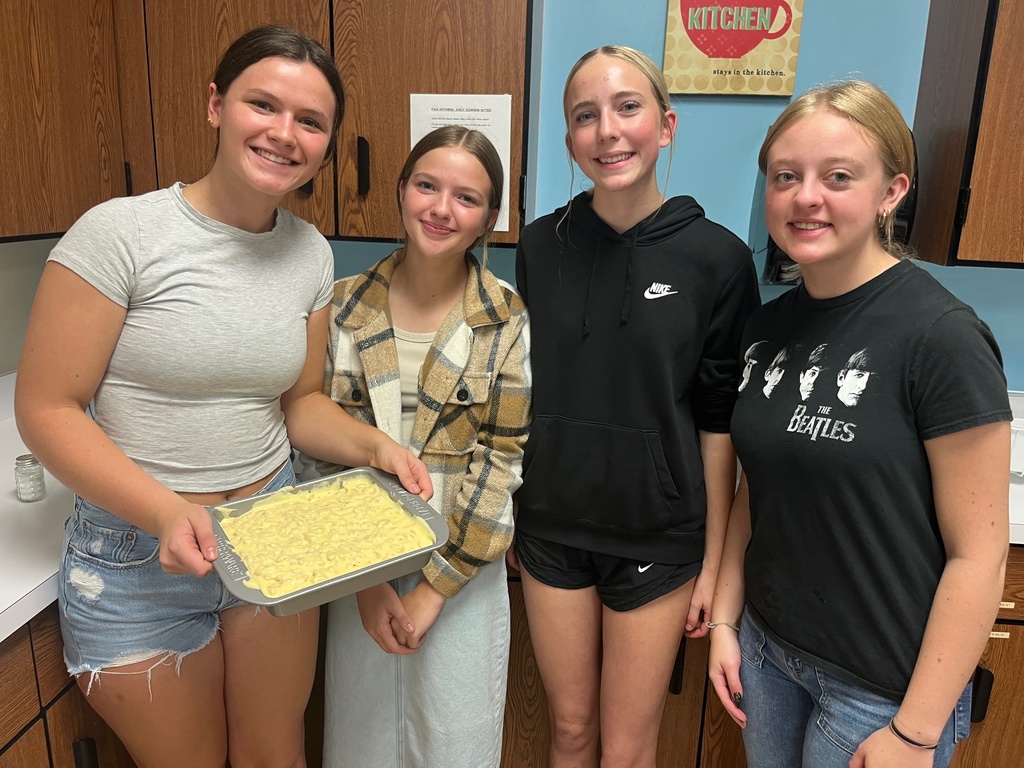 A group of four si standing together with their pan of mac and cheese.