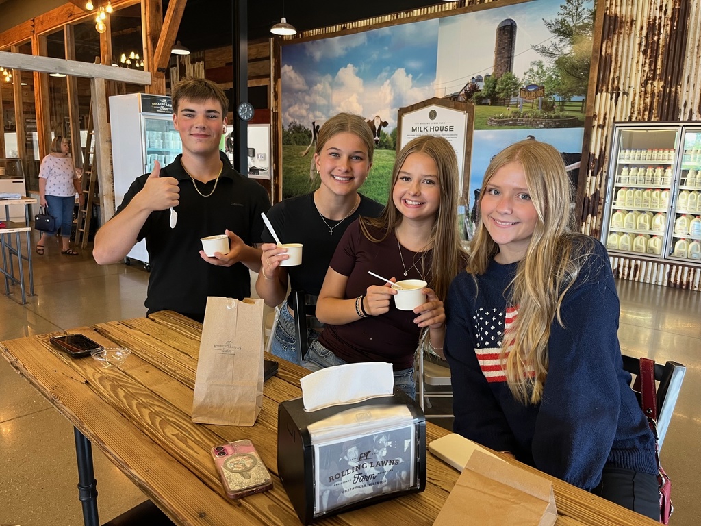 Four students are standing and eating a cup of ice cream.