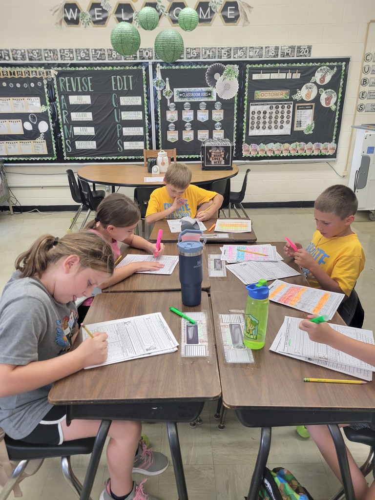 A group of students is sitting together at their desks. They are looking through papers to find clues. They are using highlighters.