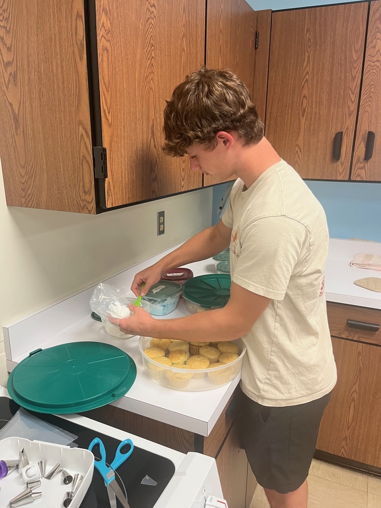 A student is filling the piping bag with white icing.