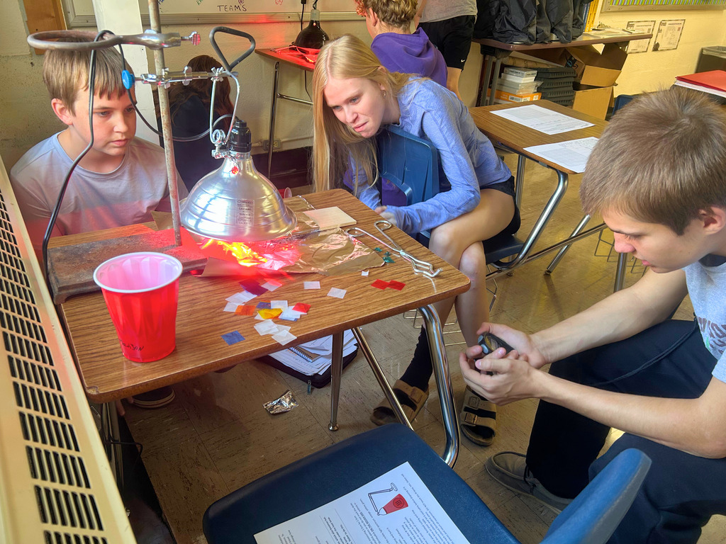 Students are watching the heat lamp. One student is timing to watch the affect of heat over a period of time.