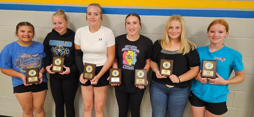 Six students are standing against a wall. They are each holding their award(s).