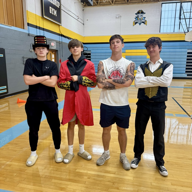 Poor students are standing side-by-side. They are each crossing their arms. One is a ring leader. Another is a muscle man and two others are circus characters as well.