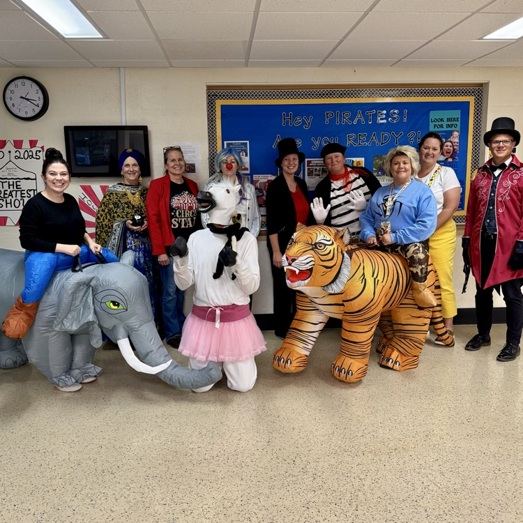 The staff is all dressed as circus characters. Some are writing elephants, and tigers. Others are clowns. And there is a white pony in the middle.
