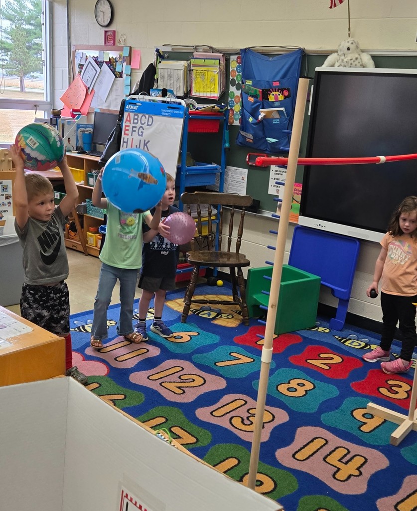 Three students are holding balls. They are getting ready to throw them over the bar.