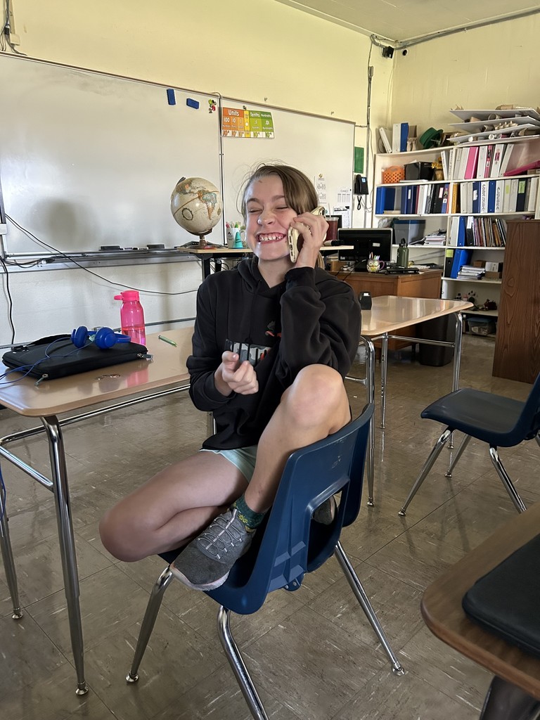 A student is calling in his order to Coffee and Creams. She is sitting at his desk.