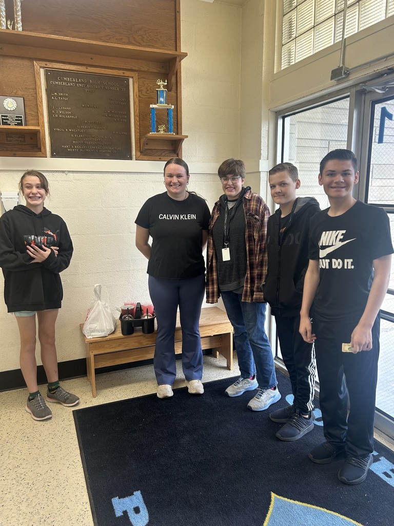 The students are standing in the foyer with the delivery worker. They were waiting to pay for their order by the door.