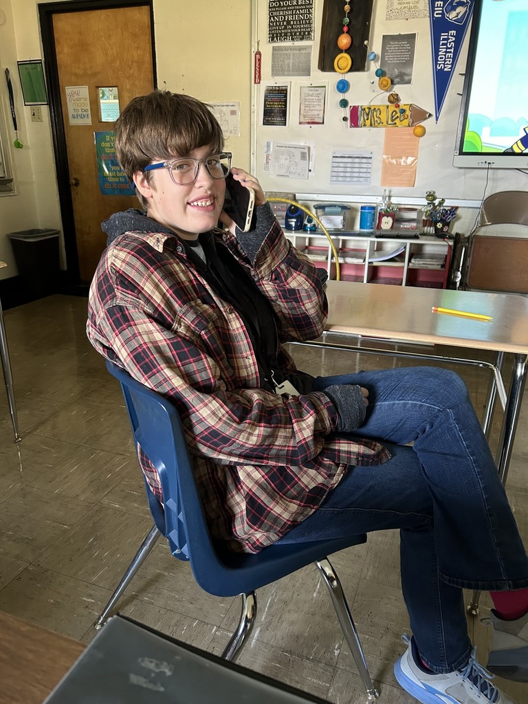 A student is calling in his order to Coffee and Creams. She is sitting at his desk.