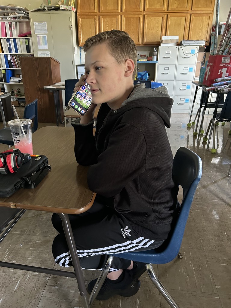 A student is calling in his order to Coffee and Creams. He is sitting at his desk.