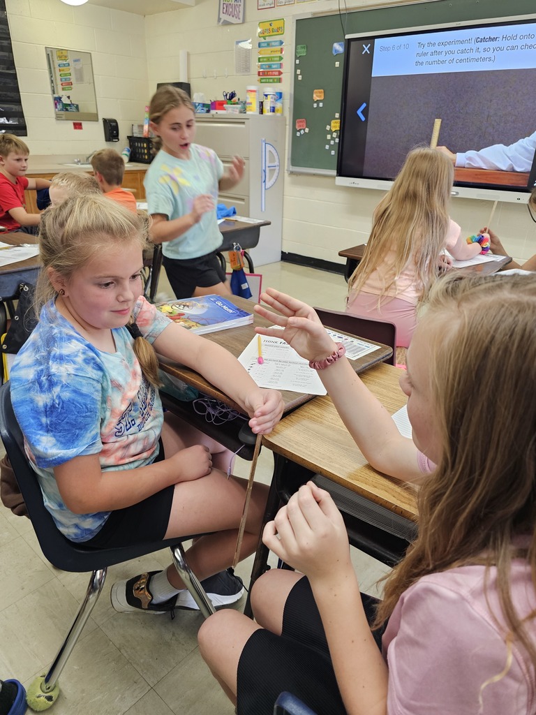 One student is holding a ruler. The second student has her hand below the ruler ready to catch it.