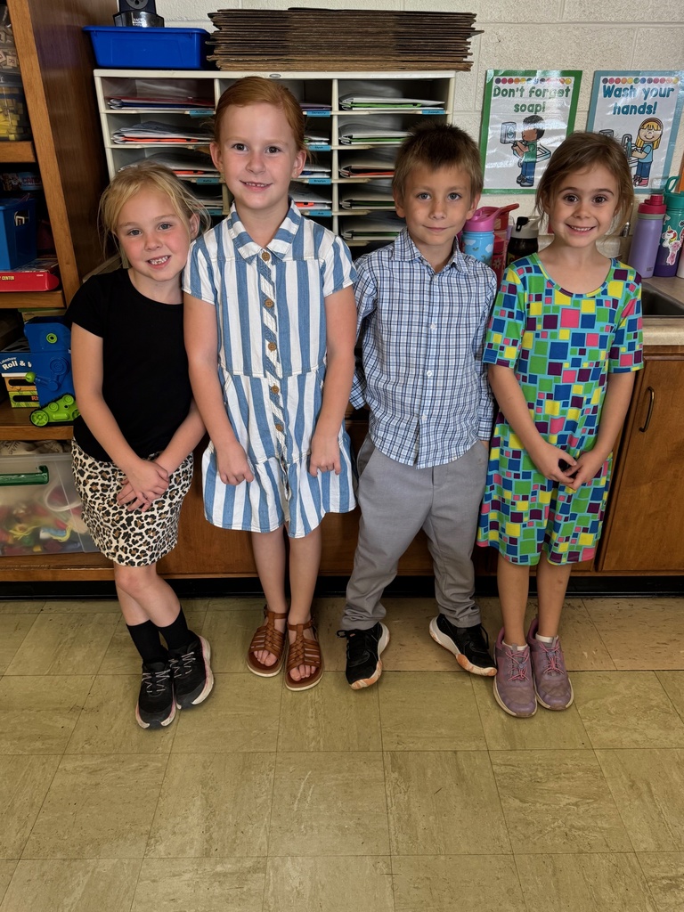 The four students are dressed as teachers. The girls are wearing dresses and the boy has dress slacks and a shirt.