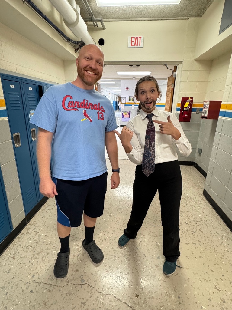 The teacher is wearing gym shorts, socks, slides and a t-shirt. The student has a beard, a tie, and dress clothes.