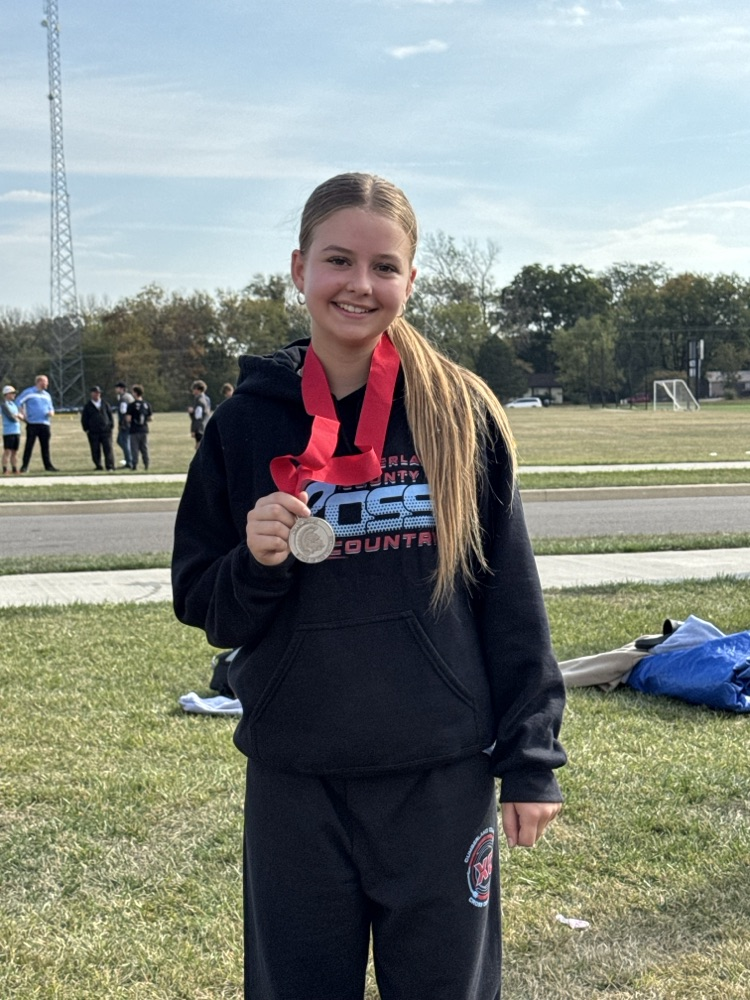 the runner is wearing her sweats. She is holding up her medal