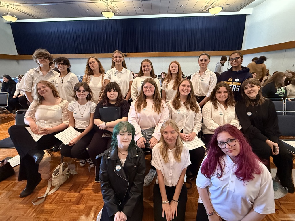The female student s are in three rows. Three are on the floor. Seven are sitting. Eight are standing.