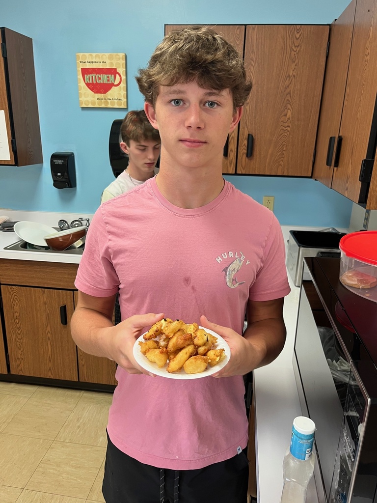 A student is facing the camera. He is holding a plate of cheese curds.